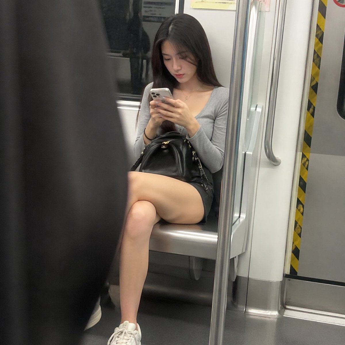 Candid Subway Photography Style Qwen Image prompt example variation 2: A realistic prompt for generating a candid-style photo of a woman on a subway looking at her phone.