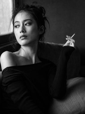 Black and White Japanese Portrait — Portrait shot on 85mm f/1.4, medium close-up of a {argument name="subject" default="Japanese woman in her late 20s"}, dark m