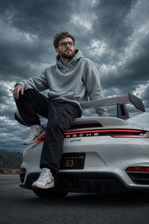 Cinematic Porsche GT3 Automotive Portrait — Ultra-realistic cinematic portrait of a young man sitting casually on the rear deck of a {argument n…