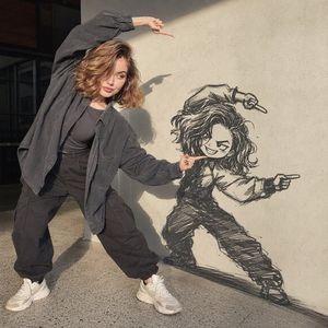 Woman Interacting with Wall Doodle — A full-body, photorealistic portrait of a stylish young woman posing dramatically beside a {argument name="wall texture" de