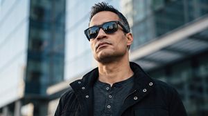 Urban Mystery Portrait — A cinematic close-up portrait of a {argument name="subject" default="man in his 30s"} with neatly styled short hair swept upward. He is