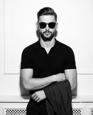 High-Fashion B&W Male Model Portrait — A confident {argument name="subject" default="young male model"} stands centered and facing the camera in a deliberately 