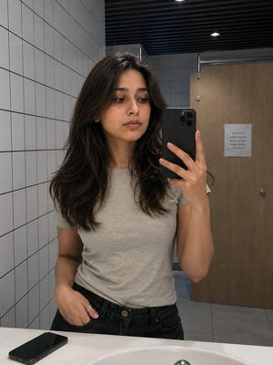 South Asian Woman Mirror Selfie — Use the uploaded image only as the facial identity reference. Preserve the person's identity with a…