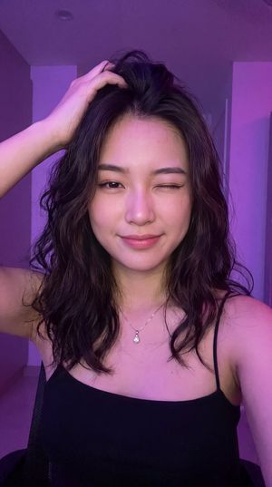 Neon Winking Selfie Portrait — A close-up portrait of a young {argument name="subject" default="East/Southeast Asian woman"} with f…