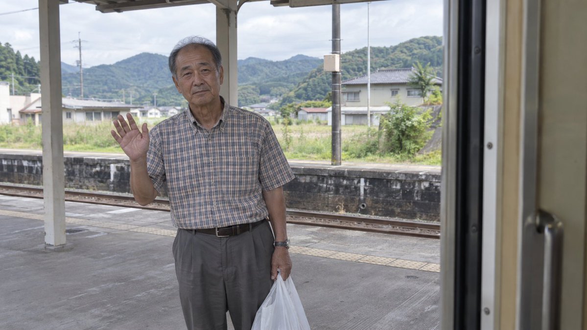 Elderly Man Waving at Rural Station